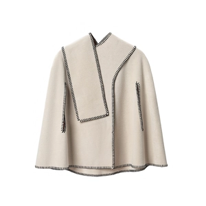 Beige poncho cape with black whipstitch edges and arm openings on white background