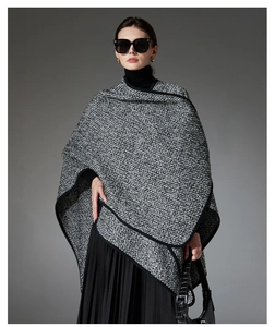 Detail of a thick black and white tweed knit wool poncho with stylish wide black trim edges
