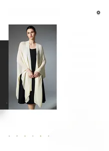 Detail of cream white knit shawl with breathable mesh texture and elegant drape over a dress