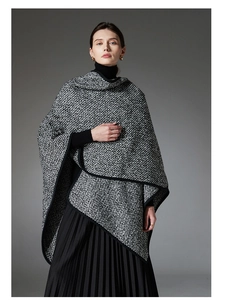 Detail of a textured black and white knit wool poncho with black contrast trim