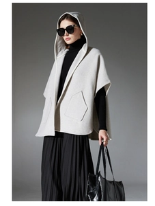 Détail d'un poncho en laine gris clair avec grande capuche, poches et finitions de qualité