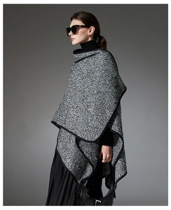 Detail of tweed wool poncho with black trim worn over a stylish turtleneck outfit