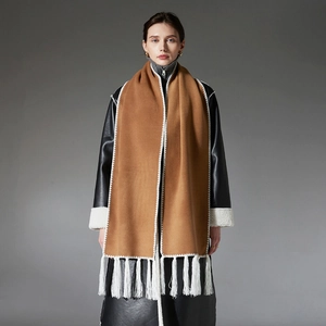 Camel winter scarf with white fringe and embroidery over a black shearling jacket