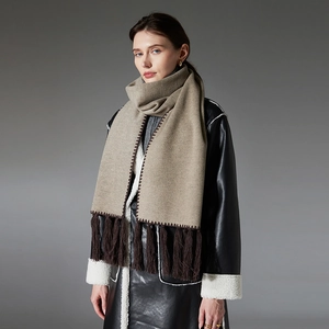 Elegant beige autumn scarf with long dark brown tassels worn over a black leather coat