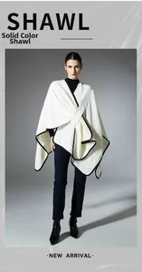 Detail view of white knitted shawl with black trim and waffle textured fabric