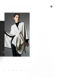 Detail view of cream plaid knit shawl cape with black trim and elegant pattern texture