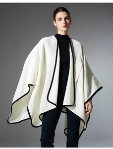 Detailed view of white knit shawl with contrast black edge trim and fine knit texture