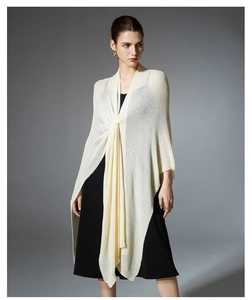 Detail of elegant beige knitted shawl featuring a stylish twist knot and draped texture