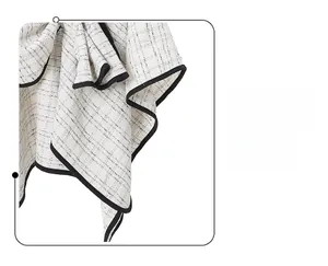 Detailed macro view of beige and black tweed fabric texture with premium stitched edge finish