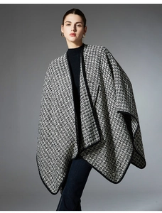 Close-up of black and white tweed texture on women's cape with elegant black piping detail