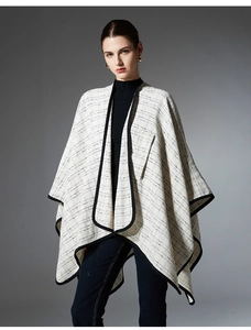 Detail shot of mid-length plaid shawl wrap with black trim and beige grid pattern