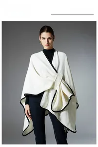 Detail of white knit shawl with black trim showing asymmetric drape and grid texture