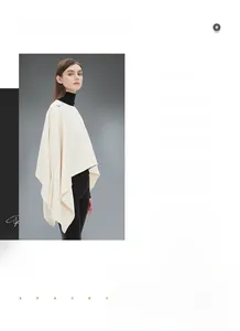 Dettaglio di un poncho in maglia crema con eleganti bottoni argentati sulla cucitura della spalla