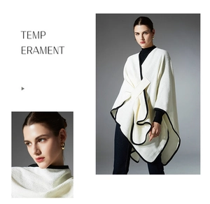 Detail of white knit shawl with black trim showing texture and tie-front closure design