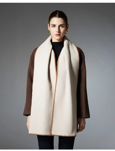 Detail of premium beige scarf with orange geometric embroidery and brown wool coat