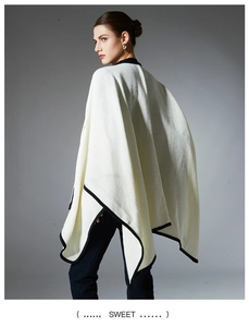Detail view of white knit shawl with contrast black trim and premium textured fabric