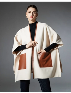 Detail view of women's beige wool cloak featuring brown leather pockets and edge binding