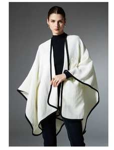 Detailed macro view of cream knit shawl with contrasting black stitched edges and texture