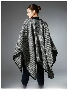 Back view of a black and white knit poncho with wool blend fabric and black piping