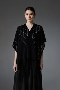 Détail d'un châle en maille noire ajourée avec motifs losanges et bordures à franges