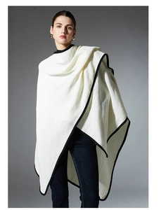 Detail of white knit shawl wrap with black trim border and thick textured fabric