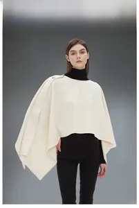 Dettaglio della mantella in lana crema con eleganti bottoni in metallo e taglio asimmetrico