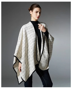 Detailed view of beige plaid shawl wrap featuring black trim and knit tweed texture