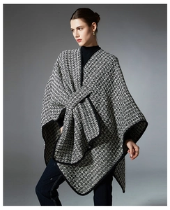 Macro shot of black and white tweed poncho featuring a decorative bow and elegant black trim