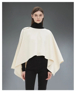 Vista dettagliata dello scialle poncho bianco crema con bottoni decorativi in argento