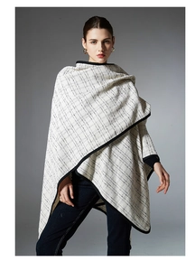 Detail of black and white checkered knit poncho featuring premium textured fabric edges