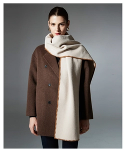 Detail of beige wool scarf with brown blanket stitch edge over dark brown pea coat