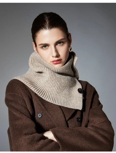 Close-up of beige ribbed knit wool neck warmer with button detail on a brown coat