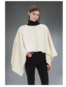Dettaglio dello scialle poncho bianco crema con chiusura a bottone e trama drappeggiata
