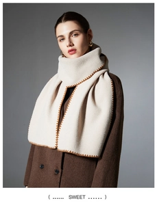 Macro shot of off-white scarf with coffee brown contrast stitch edge on wool coat