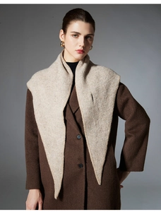 Close-up of beige knit triangle shawl texture paired with a brown wool coat and gold earrings