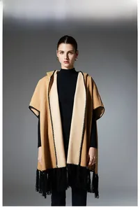 Detail of camel hooded cloak featuring contrast stitching and long black fringe trim