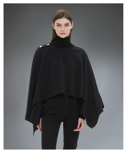 Dettaglio del poncho nero in maglia da donna con bottoni decorativi sulla spalla