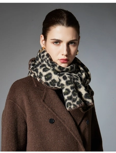 Detailed view of leopard print scarf paired with a brown wool coat and golden earrings