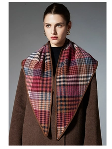 Detail of wool blend plaid shawl featuring elegant brown leather trim and colorful pattern