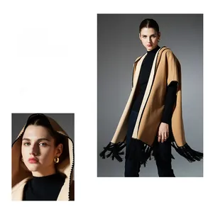 Detail of camel knitted poncho showing black tassel fringe and elegant drape texture
