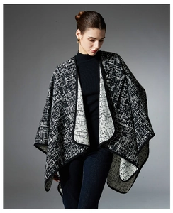 Close-up of black and white abstract plaid knit cape with elegant black piping detail