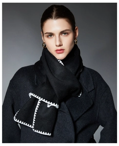 Detail of premium black wool scarf featuring white hand-stitched edges and soft knit texture