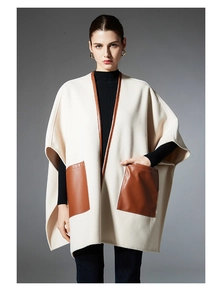 Detail of cream cape shawl showing contrast brown leather pockets and soft wool texture