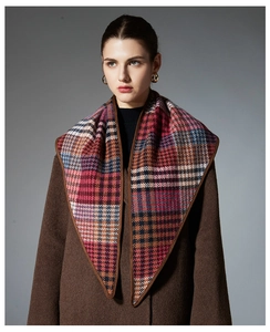 Detail of colorful houndstooth wool scarf featuring reinforced brown leather trim edges