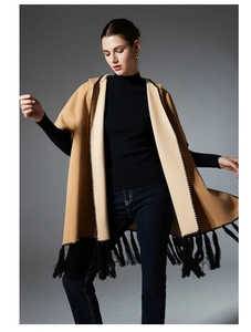 Detail of camel hooded cloak featuring black geometric embroidery and long tassel fringes