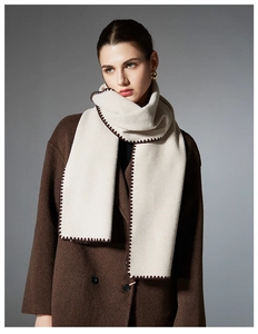 Detailed knit texture of cream scarf with dark brown contrast stitching and wool feel