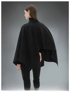 Vista posteriore di un poncho nero a maglia con trama morbida e drappeggio elegante