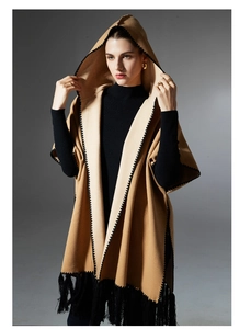 Detail of camel hooded poncho showing black zigzag edges and long stylish tassels