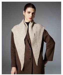 Detail of light beige knitted wool triangle shawl paired with a brown wool coat