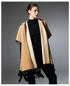Detail of camel hooded cape with black wave stitching and dense fringe hemline
